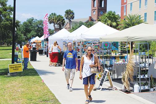 People attending the Palatka Wine Mixer in May explore the vendors who set up shop adjacent to the St. Johns River. 
