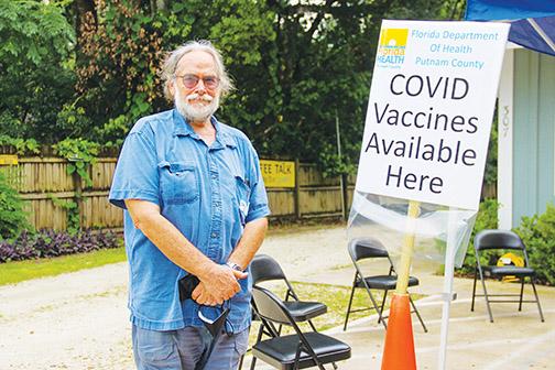 Holding a mask in his hand, Melrose Community Center Executive Director Bruce Waite stands outside the center to direct people to receive the COVID vaccine.