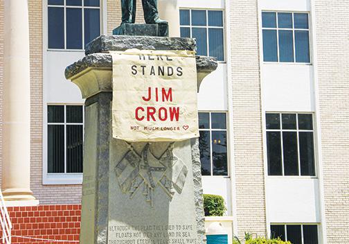 A sign is draped on the Confederate monument at the Putnam County Courthouse on Monday comparing its representation to ideals of the Jim Crow era.