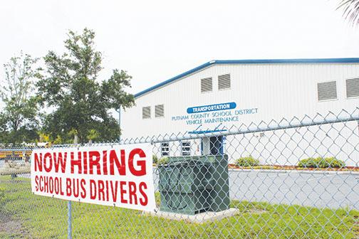 A sign advertising the need for school bus drivers hangs on the fence surrounding the bus depot in Palatka.