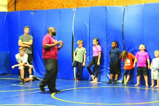 Palatka High School assistant wrestling coach Elysha Campbell goes over techniques with his young elementary school participants during Thursday’s final day of camp. (MARK BLUMENTHAL / Palatka Daily News)