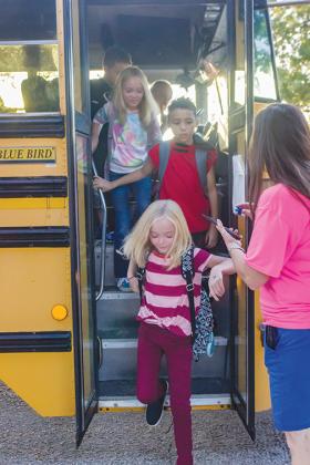 Children disembark from a school bus on the first day of school in 2019 at Interlachen Elementary School.