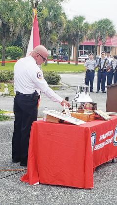 Putnam County Fire/Rescue Chief Chad Hutchinson rings a silver bell “three strikes of three” to commemorate fire personnel who answered their final call on the 9/11 attacks 20 years ago.