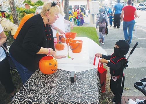 A diminutive ninja, one of more than 1,000 children who attended the 2019 Boo on the Avenue, receives candy as he strolls along St. Johns Avenue in Palatka.