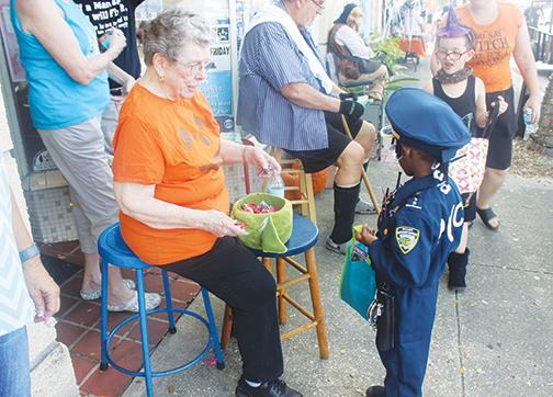 A tiny police officer takes some candy as she walks along St. Johns Avenue in Palatka as part of the 2019 Boo on the Avenue.
