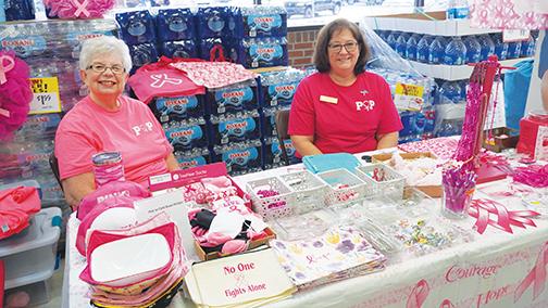 Deborah Johnson and Lucy May of Pink Out Putnam sit at their table inside Hitchcock’s supermarket in East Palatka on Saturday.