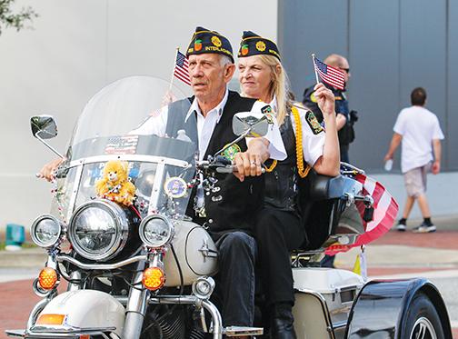 Interlachen Post 293 Commander Donald Hartsfield revs his motorcycle engine Thursday down St. Johns Avenue while his wife, Regina Hartsfield, waves two American flags from the passenger seat.