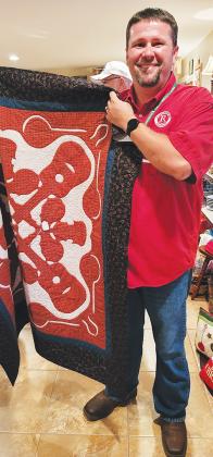 Brad Hall, executive director of the boys ranch, holds up a quilt people can win in a raffle.