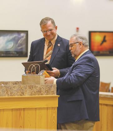 County Commissioner Larry Harvey smiles Tuesday as County Administrator Terry Suggs shows him a plaque Suggs had made to commemorate Harvey’s year spent as the Board of County Commissioners chairman.