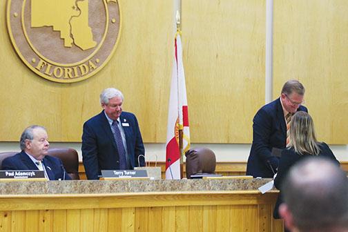 Newly-appointed Board of County Commissioners Chairman Bill Pickens, center, changes seats after he was elected to leadership.