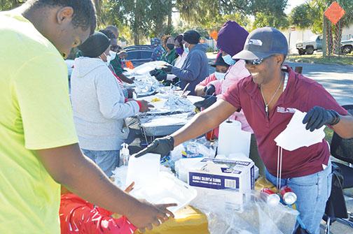 Lakesha Session hands out napkins to local residents at the annual Feed the Neighborhood event on Tuesday. 