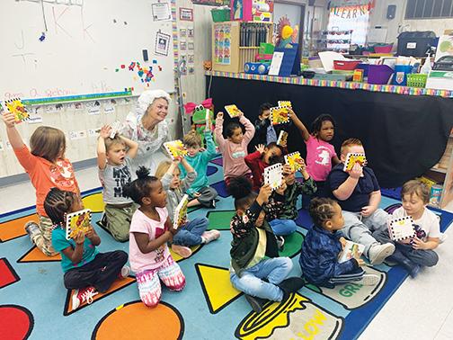Students from Mellon Learning Center in Palatka hold up their books while sitting with Mother Goose in November.