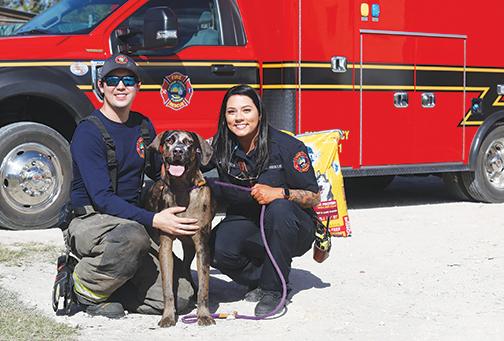 Putnam County Fire Rescue employees kneel next to one of the dogs up for adoption. County firefighters collected 3,048 pounds of pet food and 113 blankets.