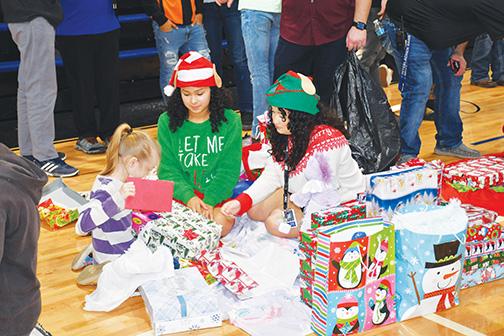 Elves Adeonna Rivera and Yalisa Maldonado gift out Christmas gifts Thursday during the school’s annual Diane Reeves Christmas Party.