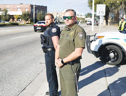 Palatka Police Department Capt. Brad Forsyth, left, and Putnam County Sheriff’s Office Capt. David Ussery watch a processional honoring a fallen Hillsborough County deputy make its way over Memorial Bridge and into Palatka.
