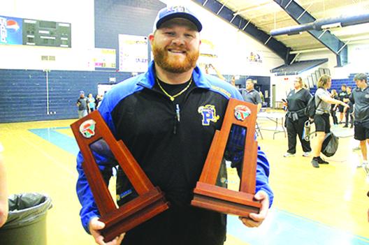 Palatka coach Dustin Whitlock holds the district meet second-place trophies his team won in both the regular competition and in the snatch competition. (COREY DAVIS / Palatka Daily News)