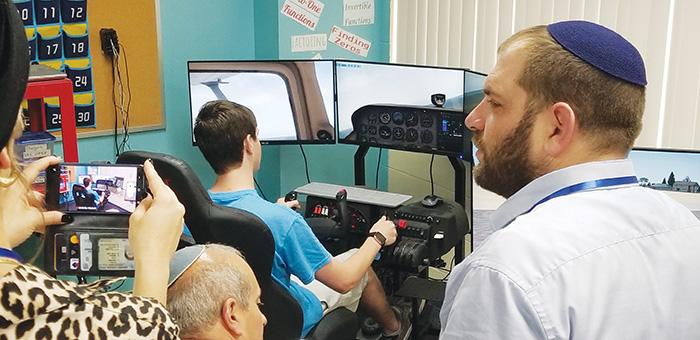 Brandon Stouffer, a junior at Q.I. Roberts Junior-Senior High School, demonstrates a flight simulator for educators from Israel on Tuesday. 