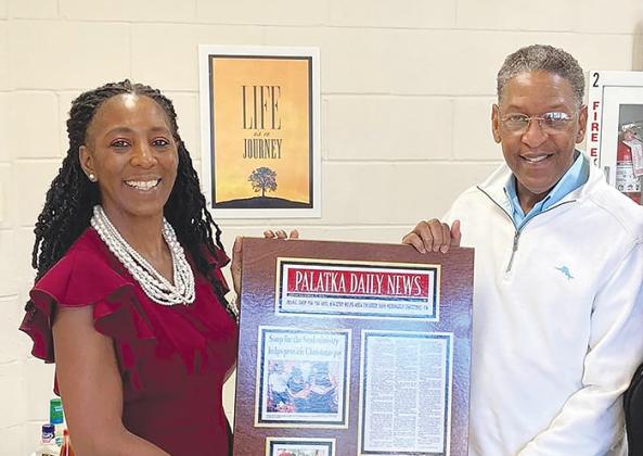 Catherine Mercer, left, is pictured with Aaron Robinson, Palatka Housing Authority’s director of social services, holding a plaque of a Palatka Daily News story that was written about Mildred Brockington’s ministry in the community to help those in need. 