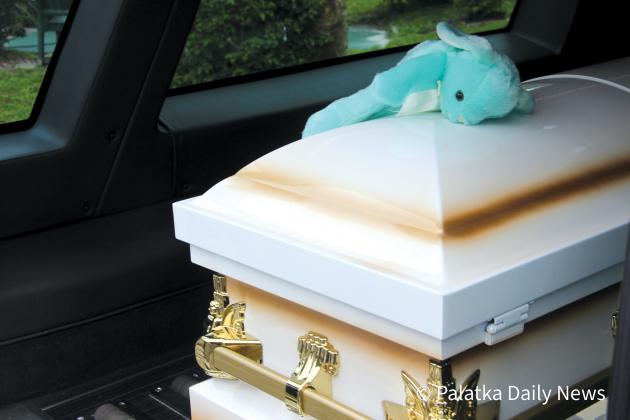 An area toddler, who knew Jose Mayo Lara Jr., placed a stuffed animal on top of Jose’s casket after it was loaded into the hearse following the funeral Mass. (TRISHA MURPHY/Palatka Daily News)