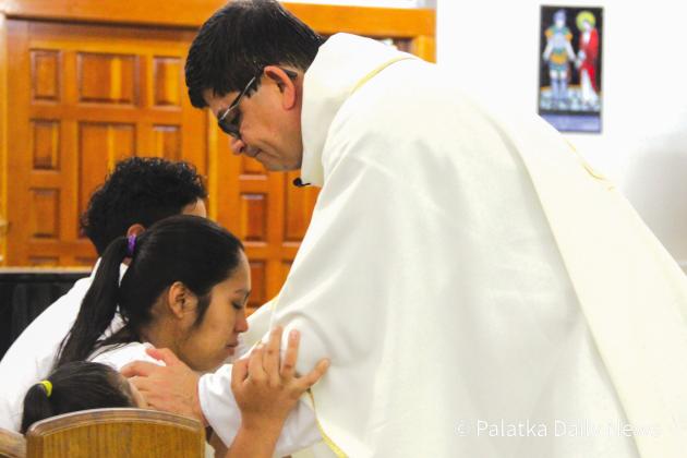 Maria Lara is comforted by Father William Villa at the funeral Mass for her young son, Jose Mayo Lara Jr. (TRISHA MURPHY/Palatka Daily News)
