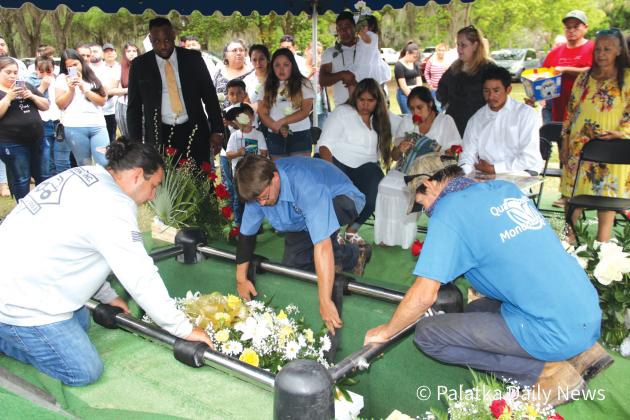Ground workers lower Jose Mayo Lara Jr.’s casket into the ground at Eden Cemetery in Crescent City. (TRISHA MURPHY/Palatka Daily News)