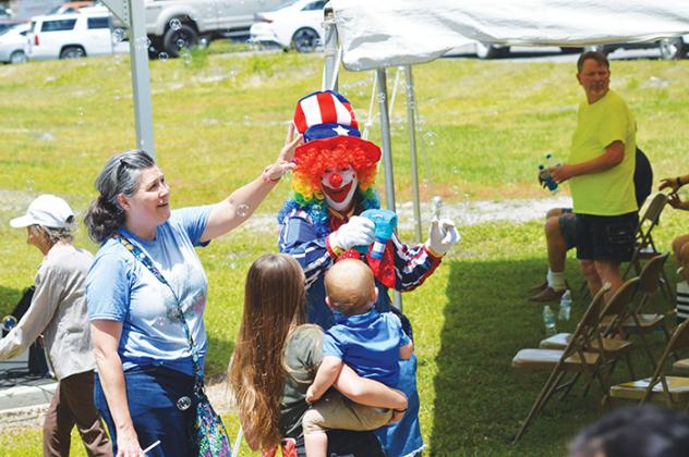 A clown entertains a child Saturday at the Bostwick Blueberry Festival.