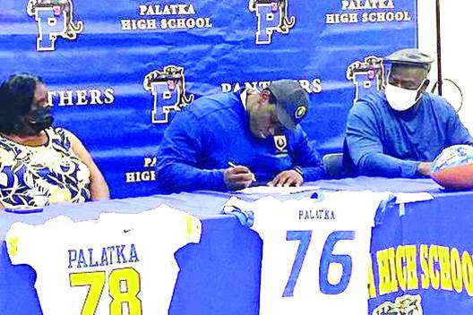 Palatka offensive lineman Daunte Wilkerson signs his letter of intent to play at Warner University in February. Watching are his mother LaTrecia, left, and father, Alvoid Maples. (Photo courtesy of Palatka Football Facebook Page)