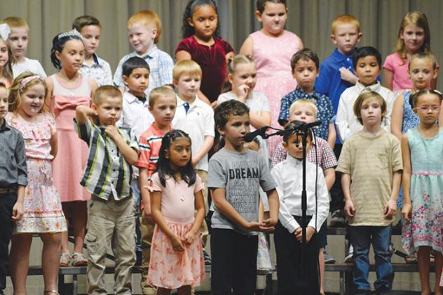 One of the school’s first graders performs his speaking part before he and his classmates resume their song.