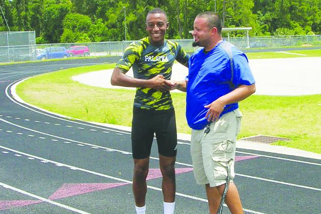 Steven Gonzalez (right) congratulates Ka’Ven Berry on being named Daily News Boys Track Athlete of the Year in 2013, the same year Gonzalez was named Daily News Coach of the Spring for the first time. Berry is now Gonzalez's assistant coach at Jacksonville Mandarin High School. (MARK BLUMENTHAL / Palatka Daily News)