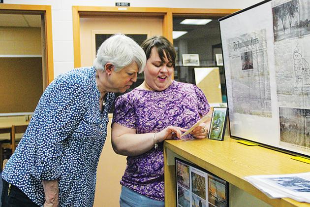 Cherie Register, left, and Rachel Cavanaugh look at historical photos from the Margary Neal Jones Nelson Archives, named for Register’s mother, in Crescent City.
