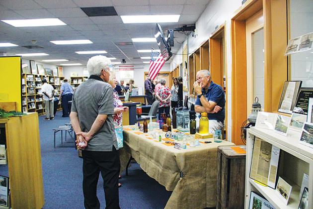 Fruitland Peninsula Historical Society members talk to bottle collector Bob Lee about his findings during the grand opening of the Margary Neal Jones Nelson Archives on Saturday. 