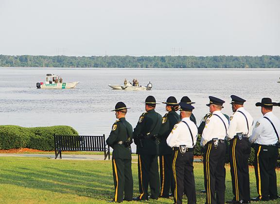 Officials stand at attention Tuesday as boats lower wreaths representing fallen officers into the St. Johns River.