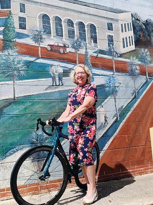 Lisa Walsh stands with her bicycle in front of a mural in downtown Palatka.