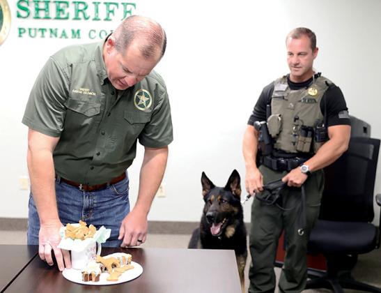 Lt. Jared Guy and Halo watch Sheriff Gator DeLoach get the dog’s retirement cake together Monday during the sendoff party.