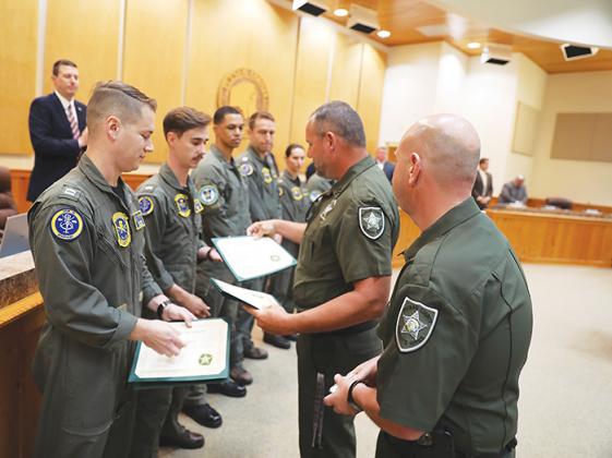 Sheriff's office officials award certificates to the Navy crews who rescued a pilot who made an emergency landing in a pond.