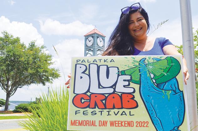 Jeannetta Salyer, the Ancient City Entertainment Group official who is organizing this year’s Blue Crab Festival, holds a sign advertising the event.
