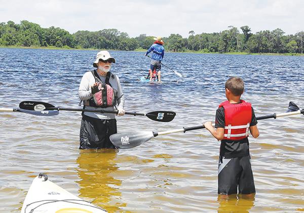 A volunteer instructs a child about how to paddleboard during last year’s Cops, Kids and Kayaks.