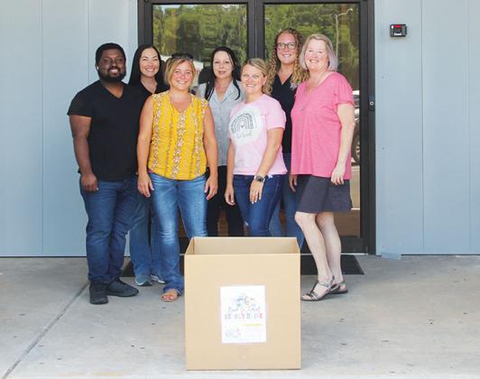 Beck Automotive Group employees pose behind a school supply drive box at Beck Automotive's administrative office Thursday afternoon.