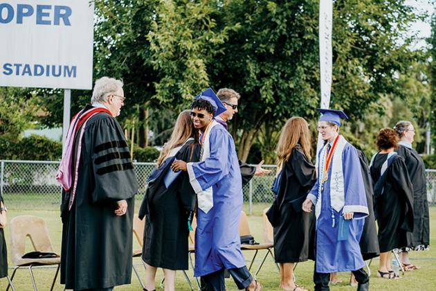 Q.I. Roberts Junior-Senior High School graduates hug and shake hands with school leaders Saturday during the commencement ceremony. 