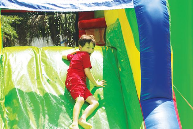 Six-year-old Izah Oshel slides down an inflatable water slide in Interlachen on Monday during the town’s July 4 event.