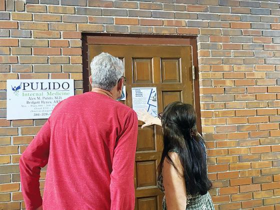Michael Mallin and Lucille Harvey, both former patients of Dr. Alex Pulido, read a sign on the late doctor’s door Wednesday informing people how to get ahold of their medical records.