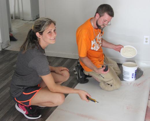 Amber Gilbert, executive director of the sober living facility Recovery Point, helps her husband Corban Gilbert lay flooring earlier this month at a "recovery community center" that Amber Gilbert plans to open in a few weeks.