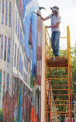 Artist Luke Taft paints part of a mural depicting Putnam House Hotel on Wednesday in downtown Palatka while balancing nearly 20 feet above the ground.