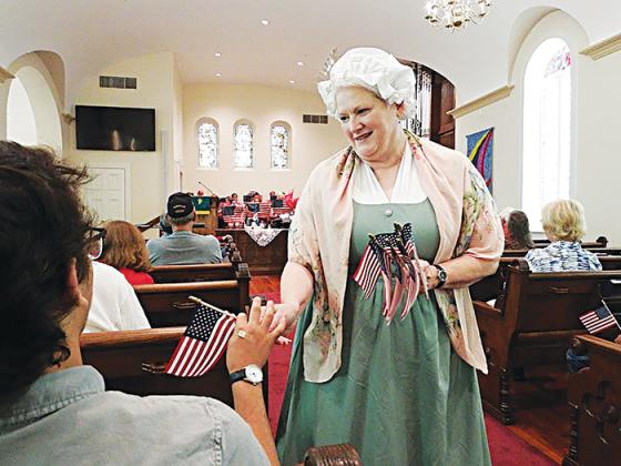 Meri Rees, regent with the William Bartram Chapter of the Daughters of the American Revolution, hands out flags at the 235th anniversary of the signing of the U.S. Constitution on Saturday at First Presbyterian Church of Palatka.