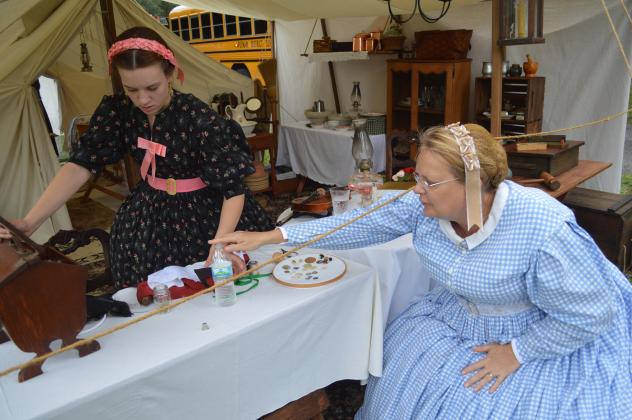 Christina Curtis, right, hands off a modern-day water bottle to her daughter, Emily-Jane Curtis, during a short break from their efforts teaching Putnam County youth about Civil War-era life during the Occupation of Palatka on Friday. (CASMIRA HARRISON/Palatka Daily News) 