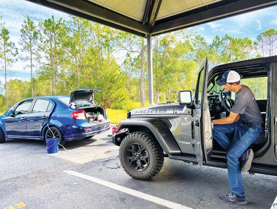 Ethan Coll, CEO of Diamond Mobile Detailing, cleans the interior of a Jeep at the Aza Health administration building in Palatka on Wednesday morning.
