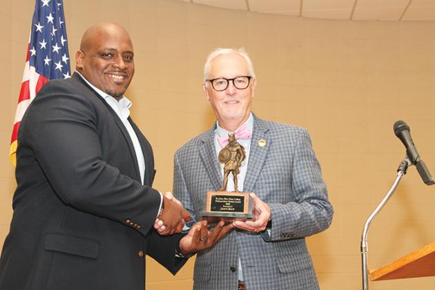 Pickens hands off the Distinguished Alumni Award to Palatka Police Chief Jason Shaw during a ceremony Friday evening in Palatka.