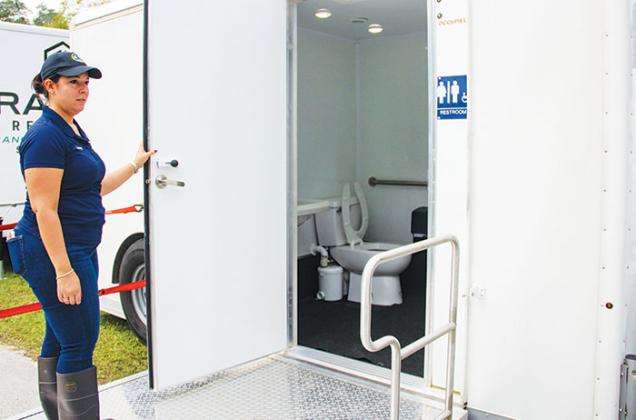 Welaka official Courtney DeSouza holds open the door to the Americans with Disabilities Act-regulated mobile bathroom at the edge of Sportsman Harbor in Welaka on Friday.