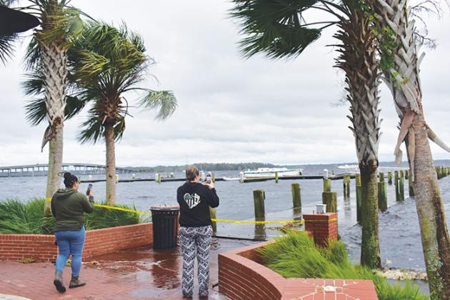 Two women record Tropical Storm Nicole’s effects on the St. Johns River as the rain begins to die down Thursday.