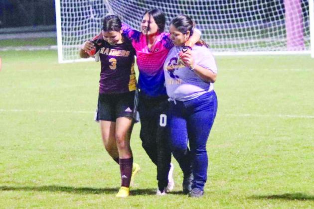 Crescent City goalie Alaina Vallaincourt is helped off the field by teammate Diana Quintana (left) and head coach Alicia Baylon after getting hurt at the start of the second half in the Raiders’ 5-0 loss to the Indians. (RITA FULLERTON / Special to the Daily News)